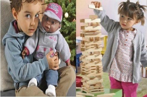 A gauche un petit garçon porte une poupée. A droite une petite fille joue avec des éléments de construction Kapla.